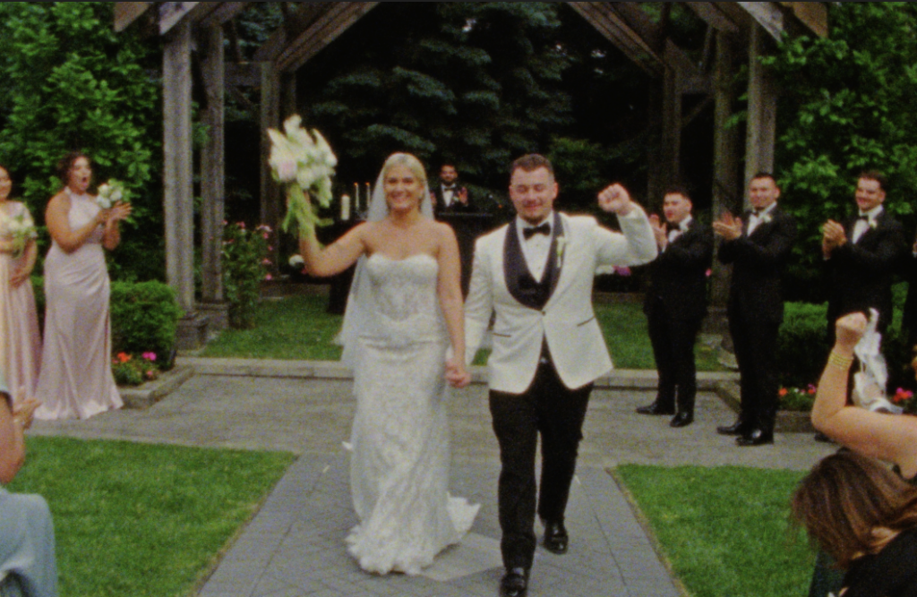 A Super 8mm still frame of the Bride and Groom cheering as they walk back down the aisle after their ceremony in Plainfield, Illinois