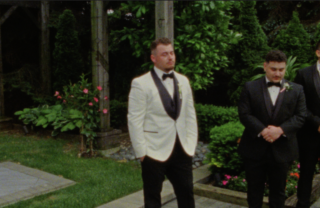 A Super 8mm still frame of the groom's emotional reaction to his bride walking down the aisle at the chapel at the farmhouse at plainfield.